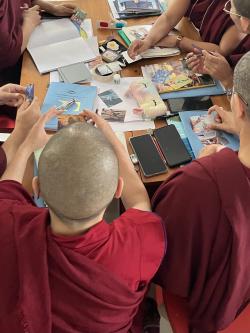 A group of Tibetan Nuns sit around a table engaged with the What Is Learning? card activity.
