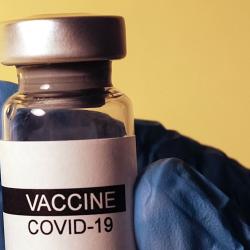 COVID vaccine vial in gloved hand Photo by Hakan Nural