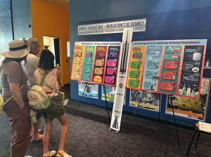 A family views a colorful, large-format radio technology timeline display at a science center exhibit.          Ask ChatGPT