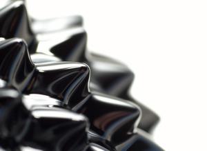 The surface of ferrofluid which is black, spikey (due to a magnetic field) and semi-glossy.