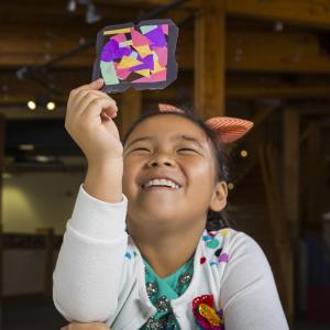 Girl looking at stained glass craft using NanoDays Exploring Materials - Stained-Glass Windows