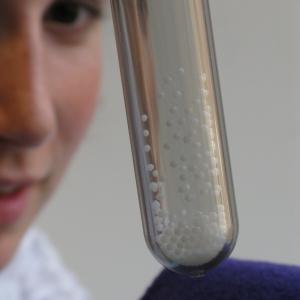 Person looking at a thick test tube filled with static charged styrofoam beads