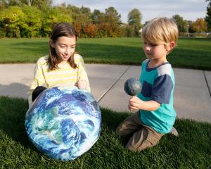 Learners use a model Earth and Moon to mimic an eclipse in a grassy field