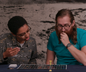 Two learners playing the game look at the board to find the planetary body in question