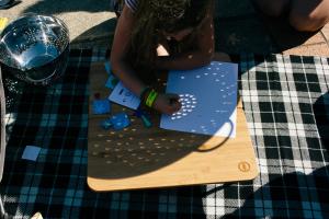 Person examining shadow patterns from a solar eclipse through a collander