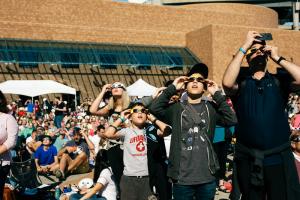 Museums visitors wearing eclipse glasses watch the 2017 solar eclipse