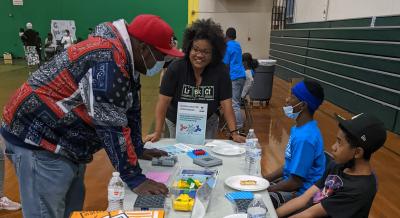 Visitor Checks out a vaccine antibody activity with volunteers and a Lawrence staff member facilitating. 