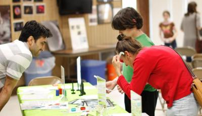 Visitors wearing 3D glasses with examining microscopic photos from a past NanoDays event at Highland Road Park Observatory in Baton Rouge, Louisiana