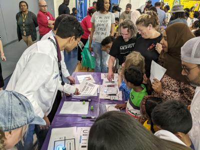 Greensboro Science Center family science night with families crowded around an hands-on activity table
