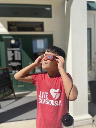 Young teen wearing safe solar viewing glasses during an outdoor event for the 2023 Annular Solar Eclipse.
