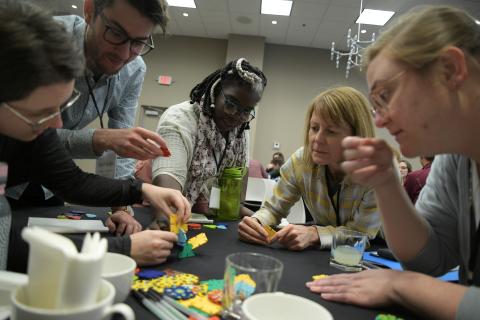 Cohort B fellows from 2019 gathering around a table for an activity