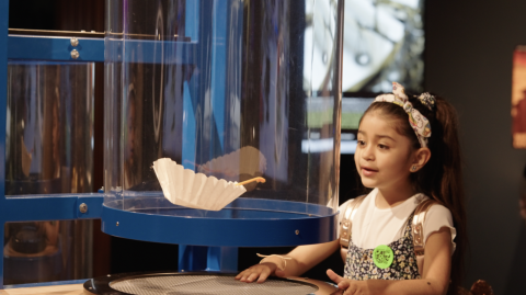 Young Mission Future exhibition visitor interacting with air tube