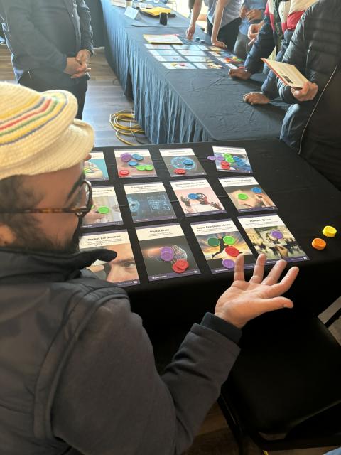 Neuro Futures Card Game on Table with Participant Gesturing to Inquire More