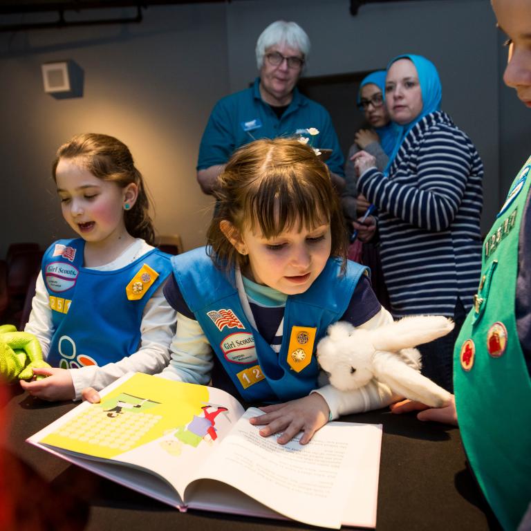 Two girl scouts reading a book