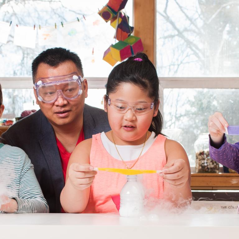 Group of children and adults using dry ice to make bubbles in Explore Science Let's Do Chemistry Sublimation Bubbles activity