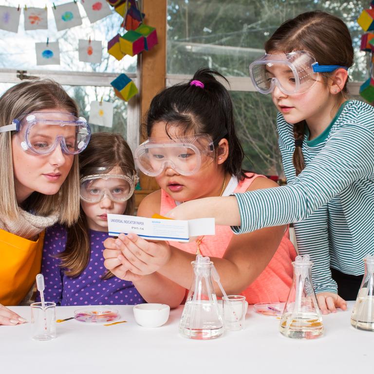 Children and and facilitator examining color changes on a piece of paper 