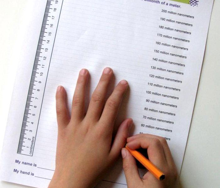 Hand being measured in nanometers with paper and pencil