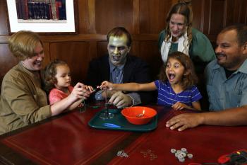 Children with surprised faces and adults using the Frankenstein kit Battery Stack activity  - adults dressed as Mary Shelley and the Monster