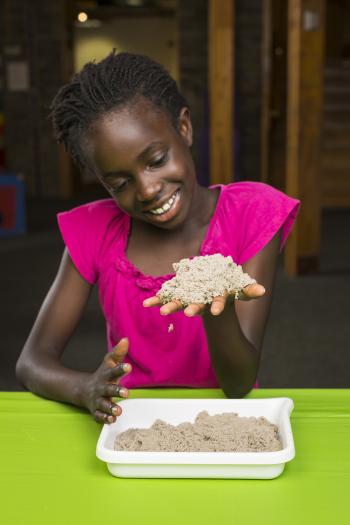 girl in pink shirt holds kinetic sand