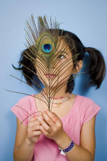 Girl in a pink shirt with staring at a peacock feather