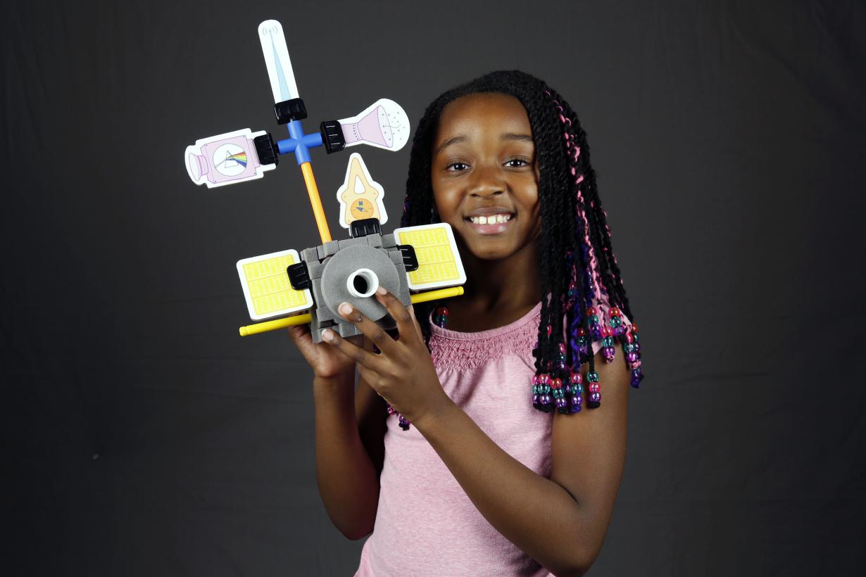 Girl holding a model of a spacecraft she built with Design Build Test engineering activity