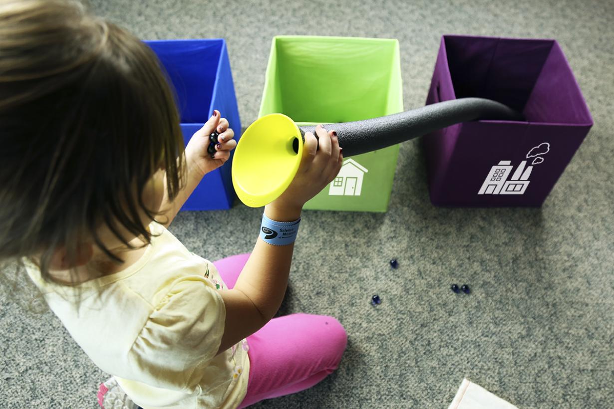 Child using putting marbles into tube with funnel in Water Roll SustainABLE kit activity