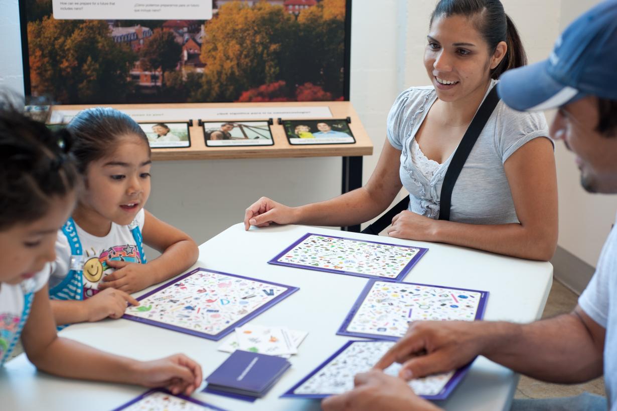 Two young learners and two facilitators look for an image hidden within their I Spy Nano mat