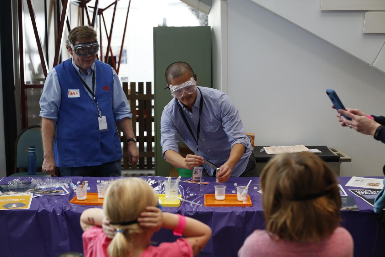 A facilitator loads a small plastic tube with fizzing solution that will pop the cap off in front of an audience of learners