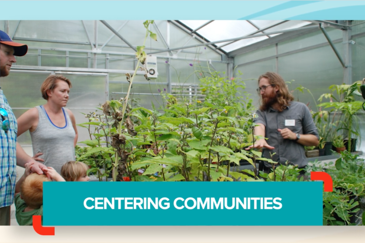 Museum educator talking with people in a greenhouse with plants