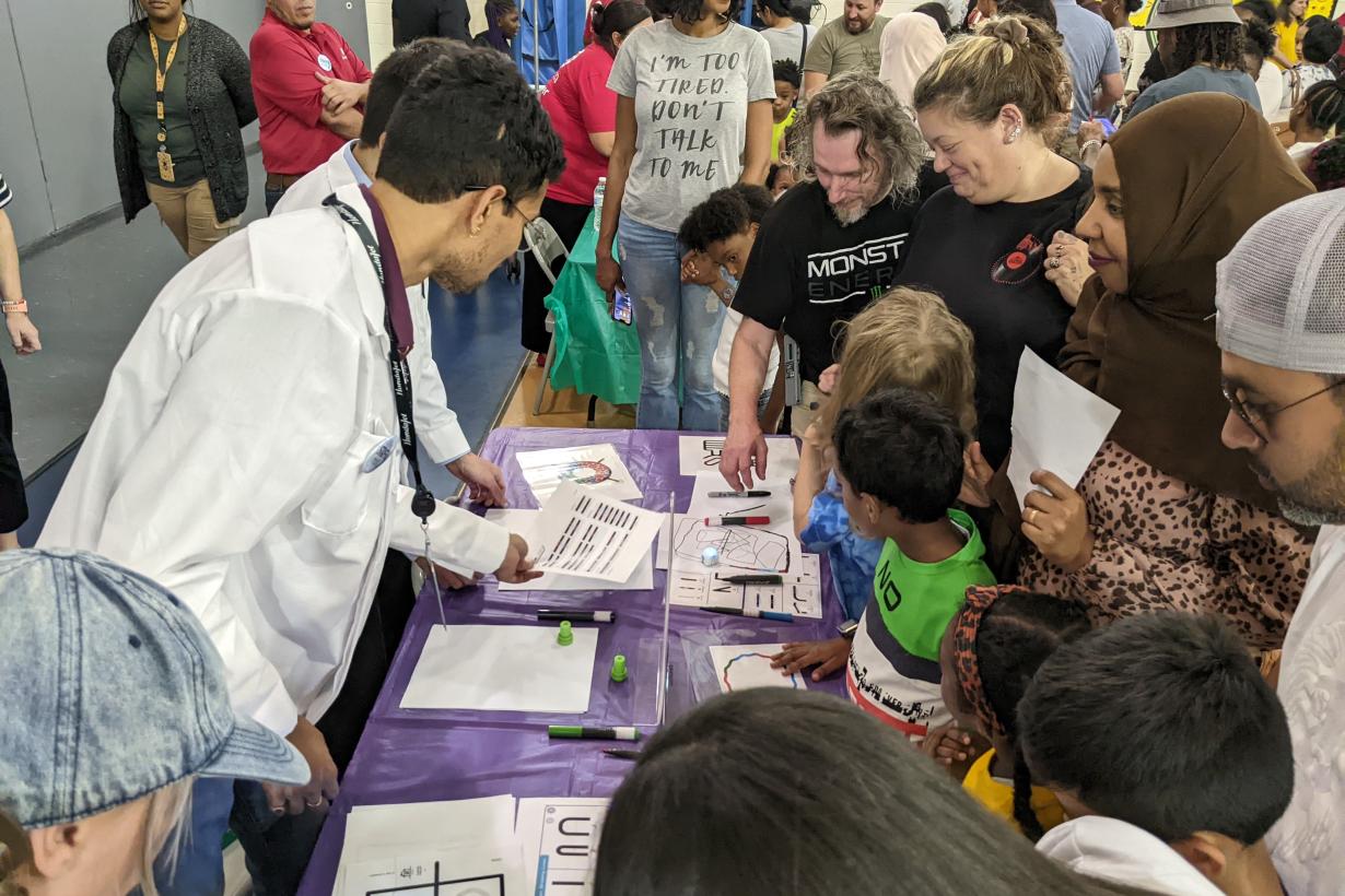 Greensboro Science Center family science night with families crowded around an hands-on activity table 