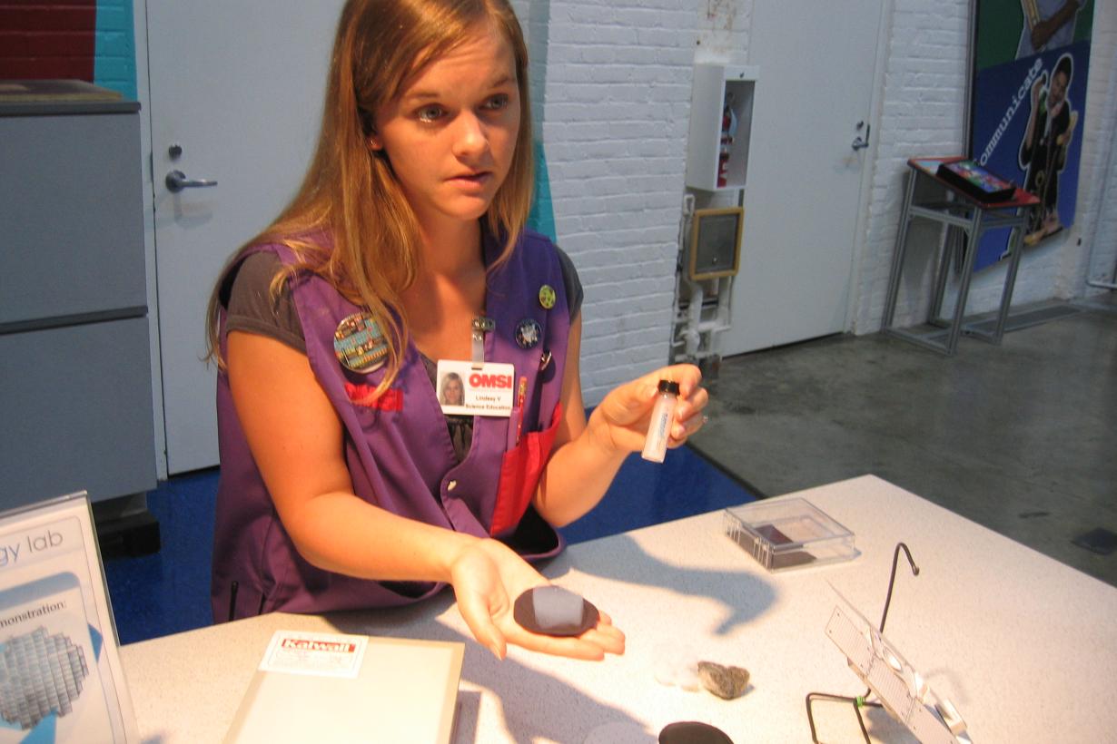 Faciltator at a table holding aerogel in the palm of her hand