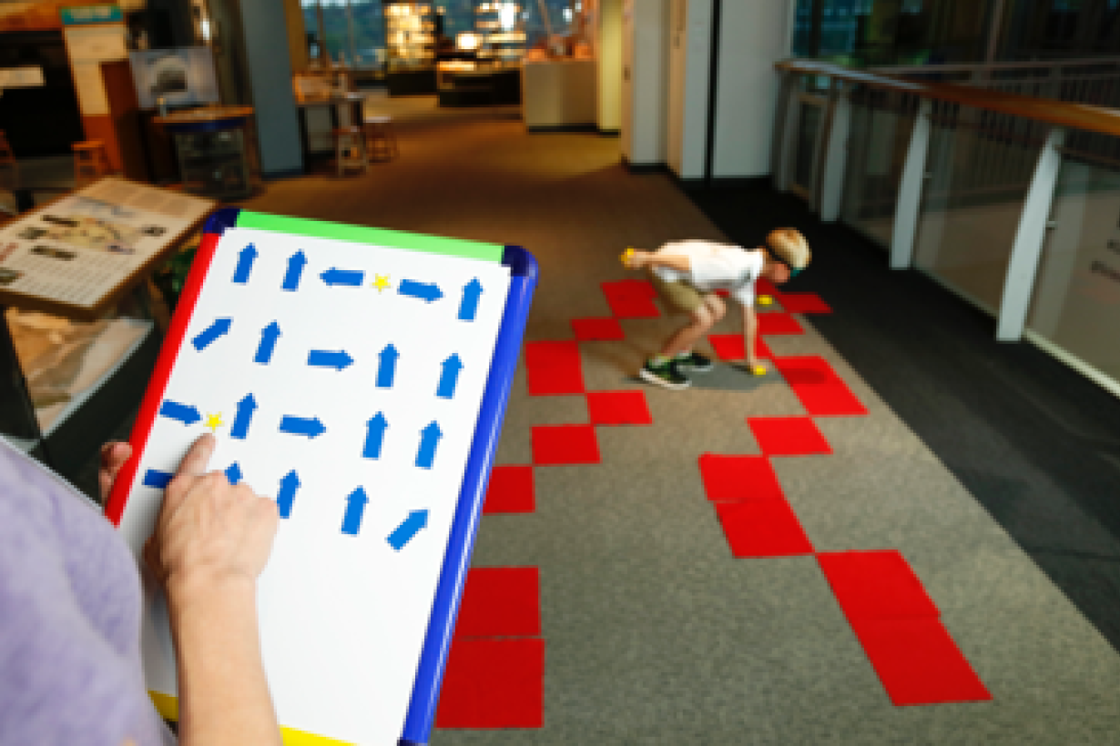 A learner gives commands to another learner who is blindfolded and is navigating a obstacle course. 