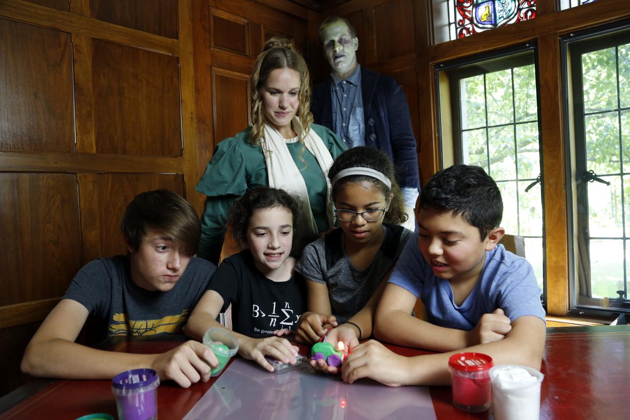 Children and adults using Frankenstein Dough Creature activity - costumed adults dressed as Mary Shelley and Frankenstein monster