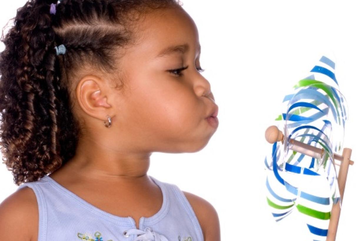 A learner blows air on a pinwheel