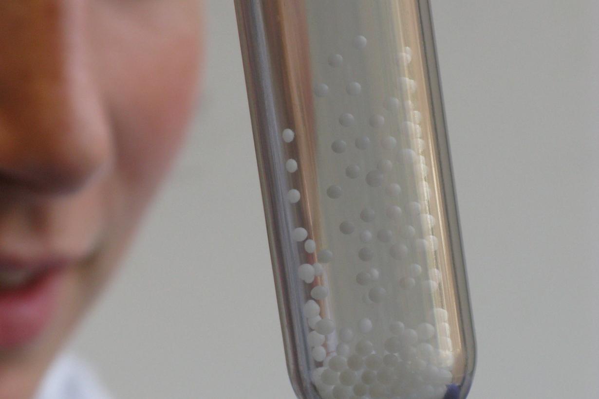 Person looking at a thick test tube filled with static charged styrofoam beads