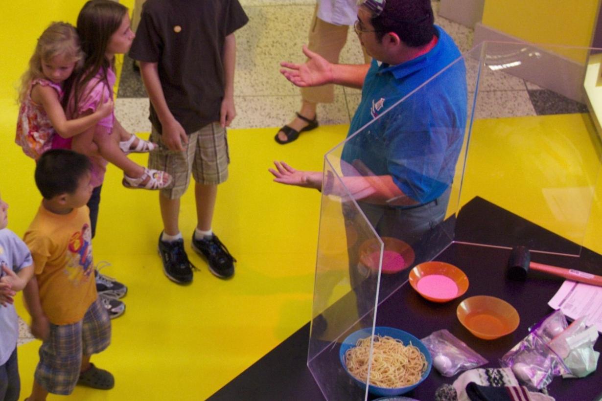 A docent is giving the liquid armor activity to an audience.