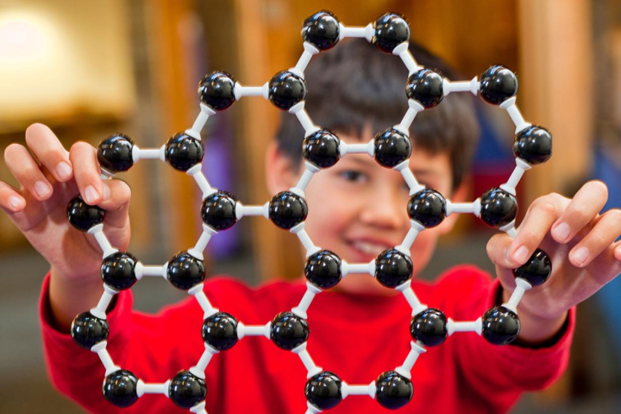 Learner holds up an atomic structure model of graphene