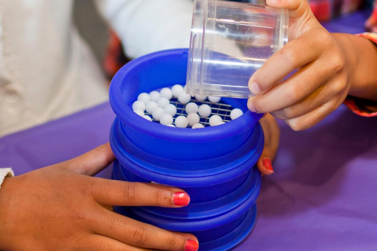 Learners pour beads into a sieve filter to sort by size