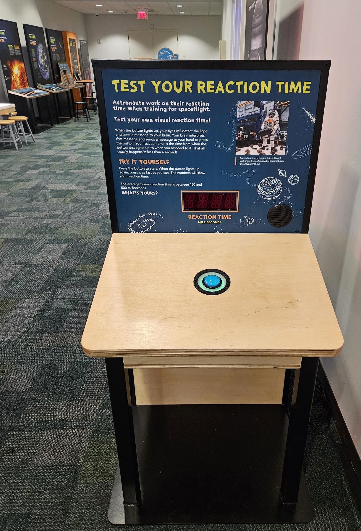 Exhibition component with a tombstone-style graphic and plan table with only one large blue button. Only visible text reads "Test Your Reaction Time"