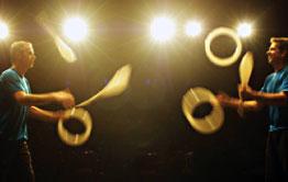 two men juggling props while on stage