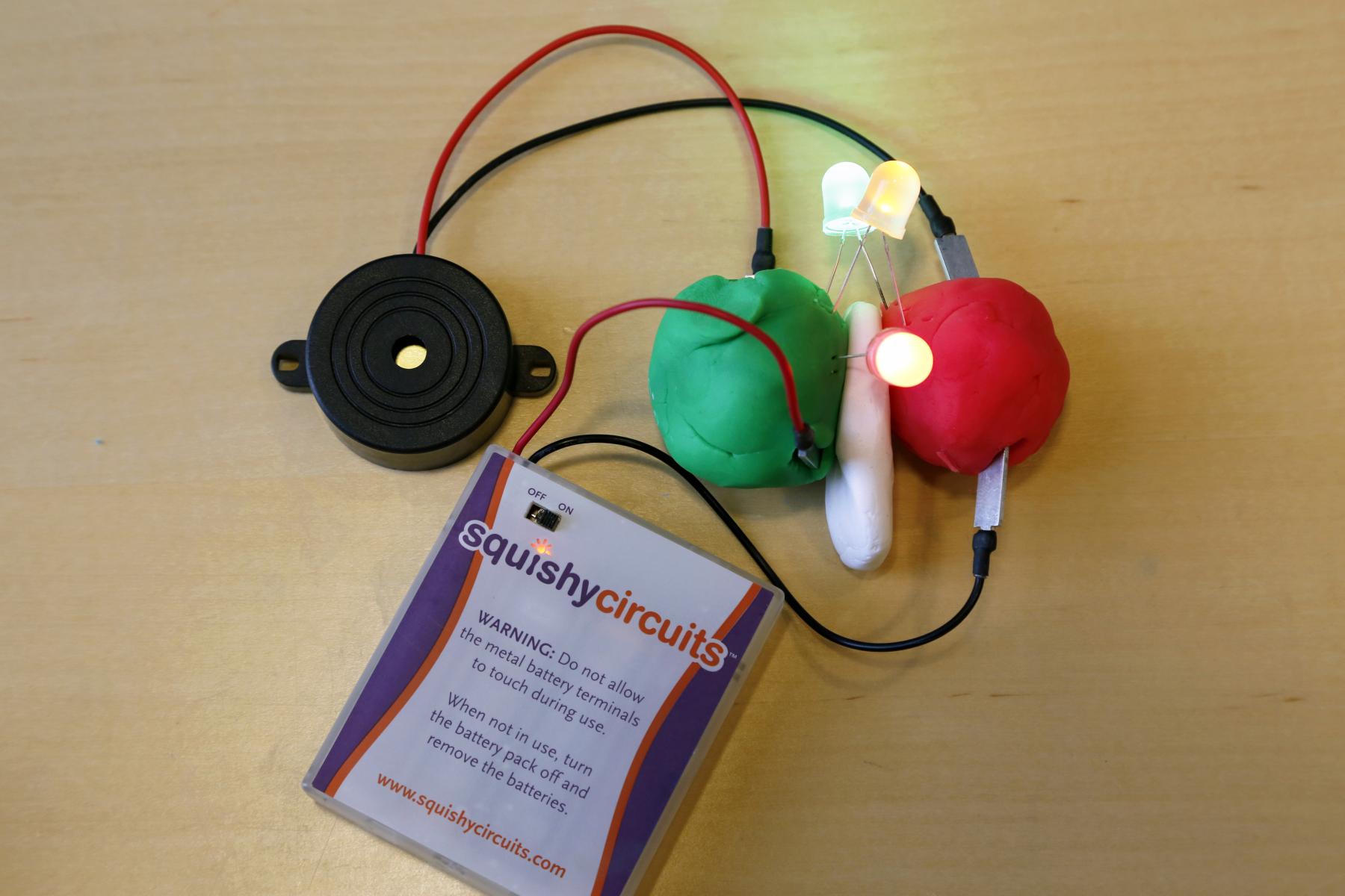 Lights, buzzer, and squishy circuit battery pack with wires connected to dough