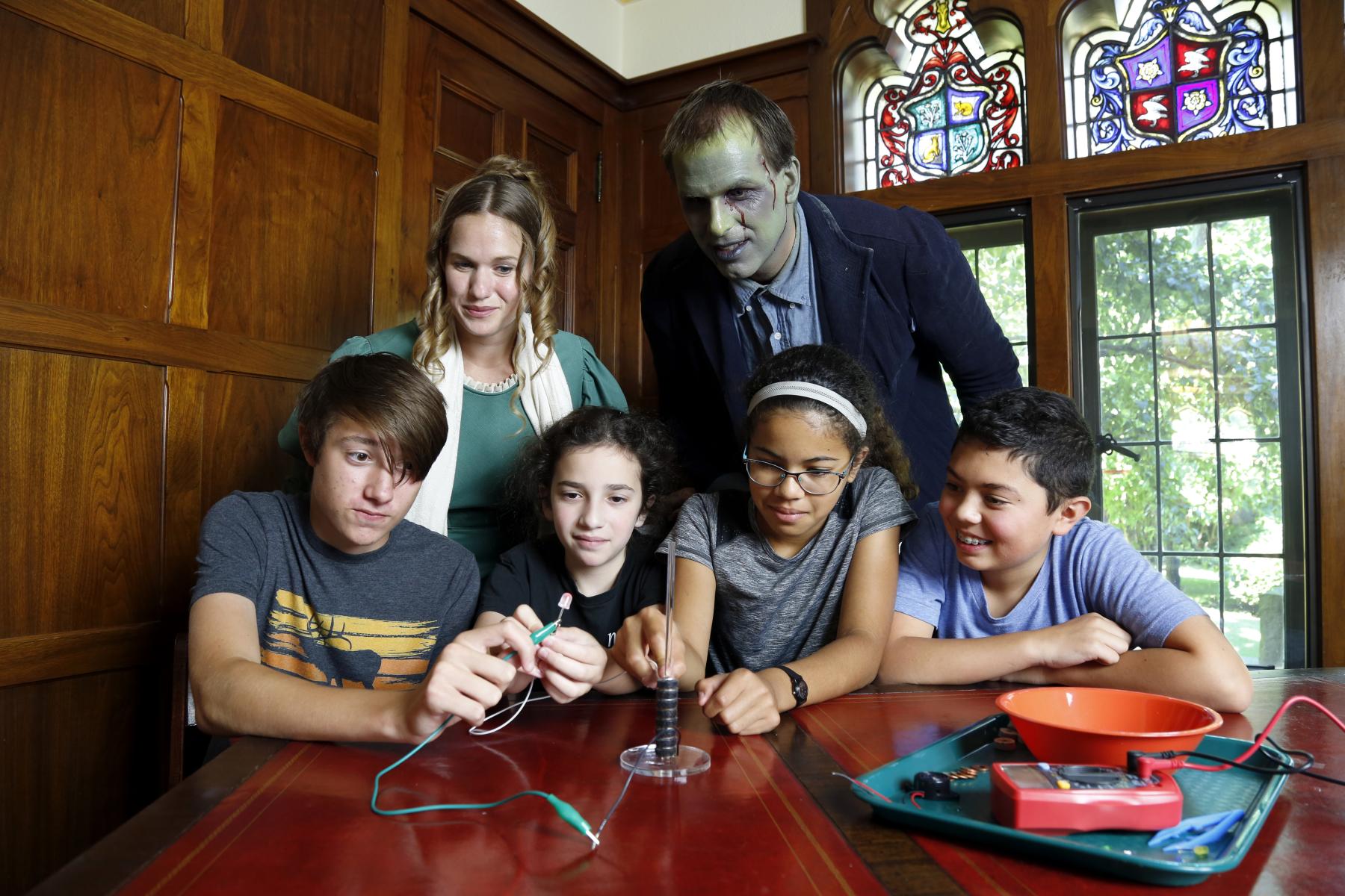 Mary Shelly, her monster, and young visitors using the battery stack activity