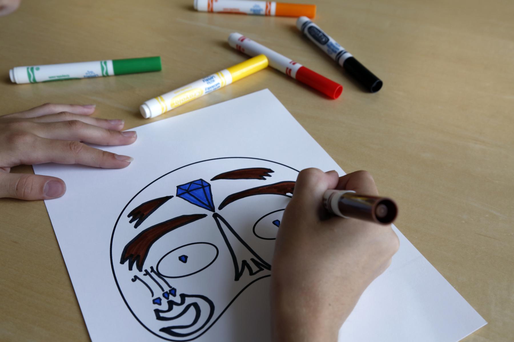 coloring a mask on a table with markers