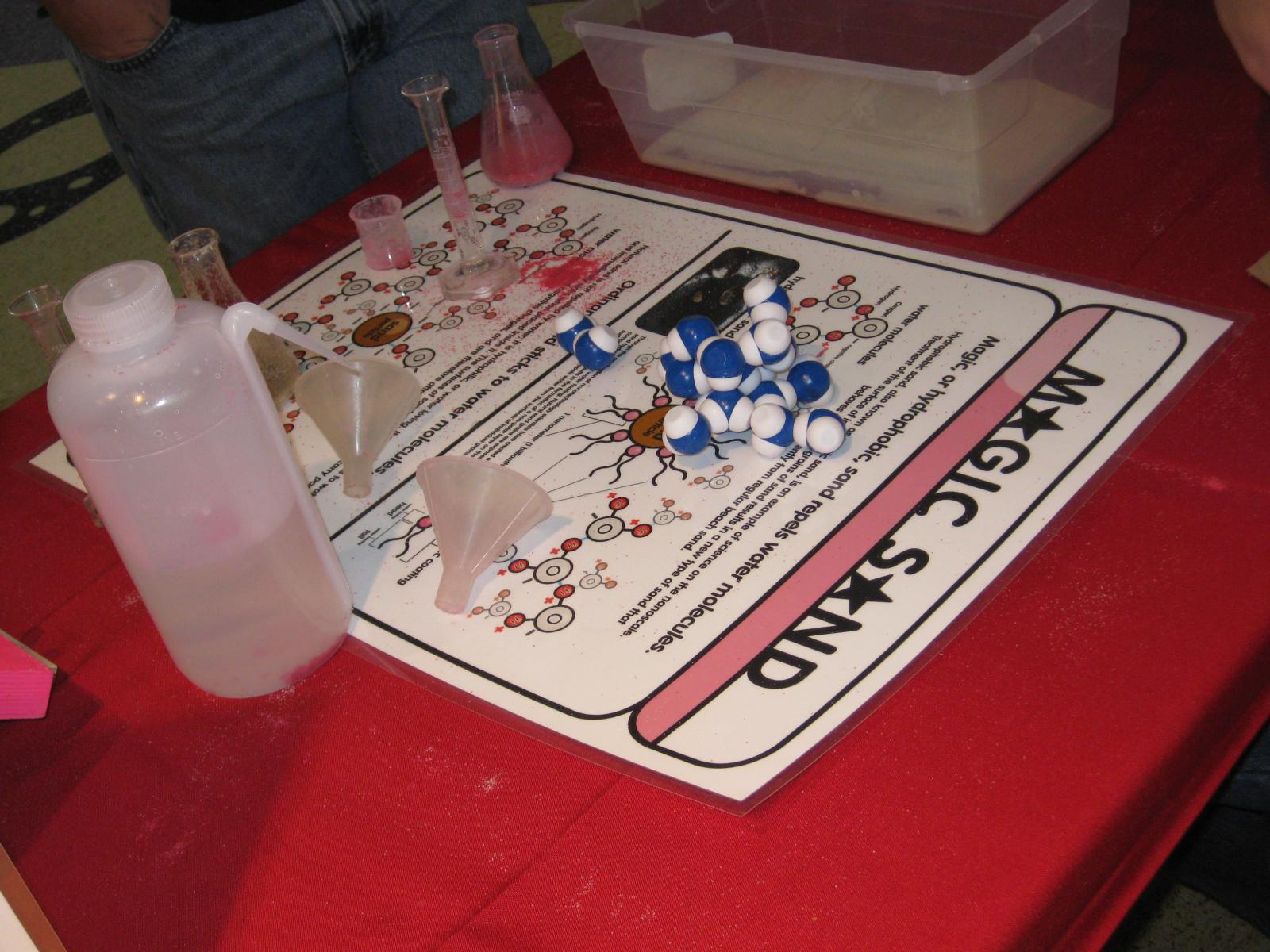 Activity materials on a table including magic sand, water, and an information sign