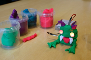 A dough creature with eyes lit up next to open dough containers 