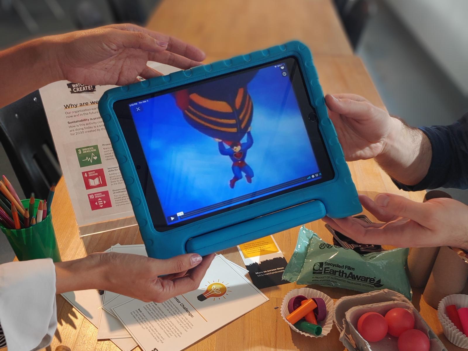 two learners holding and watching a video on a tablet