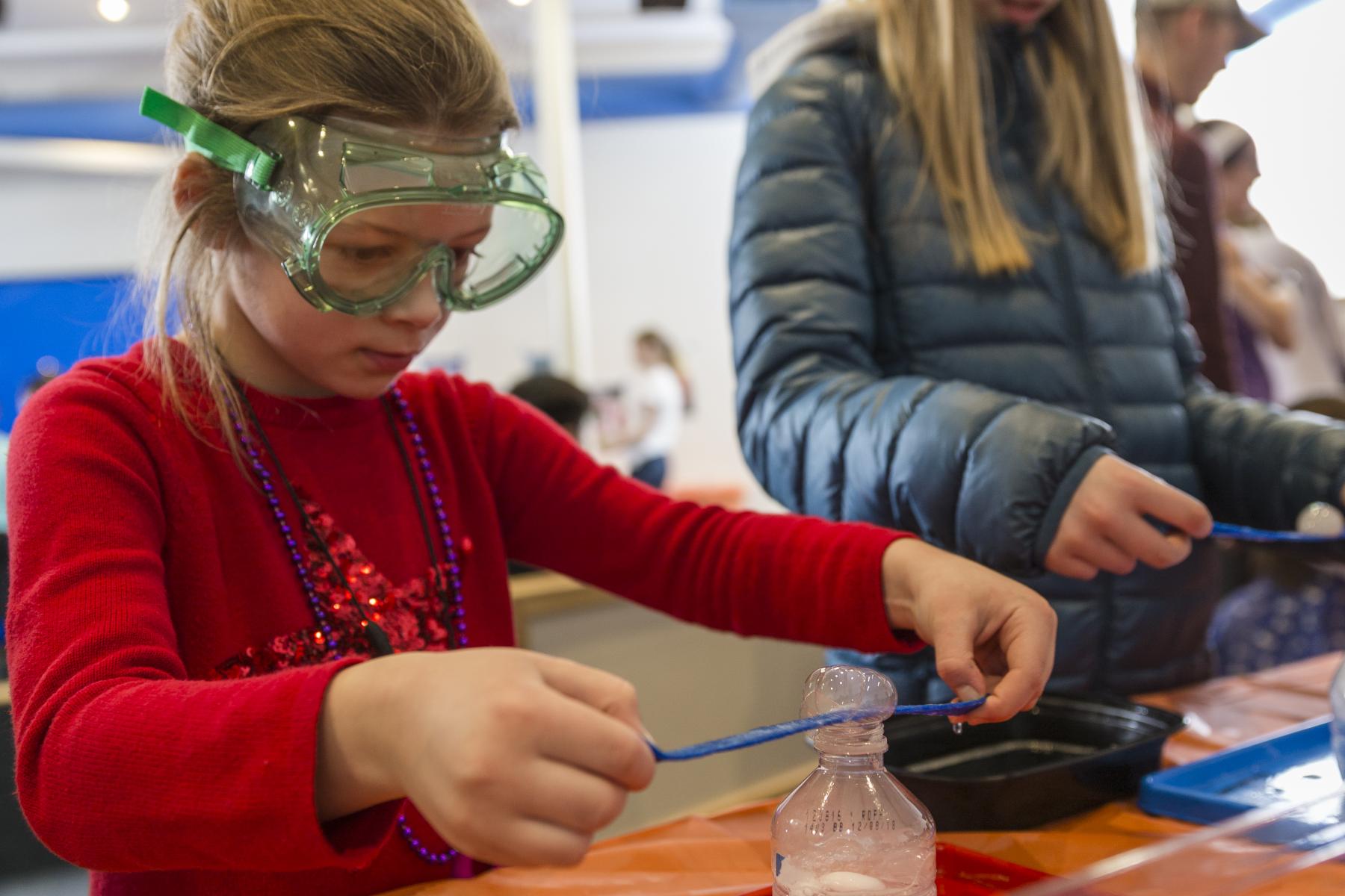 Two learners wearing goggles, placing strips of paper on bubbles bade by dry ice and soapywater 