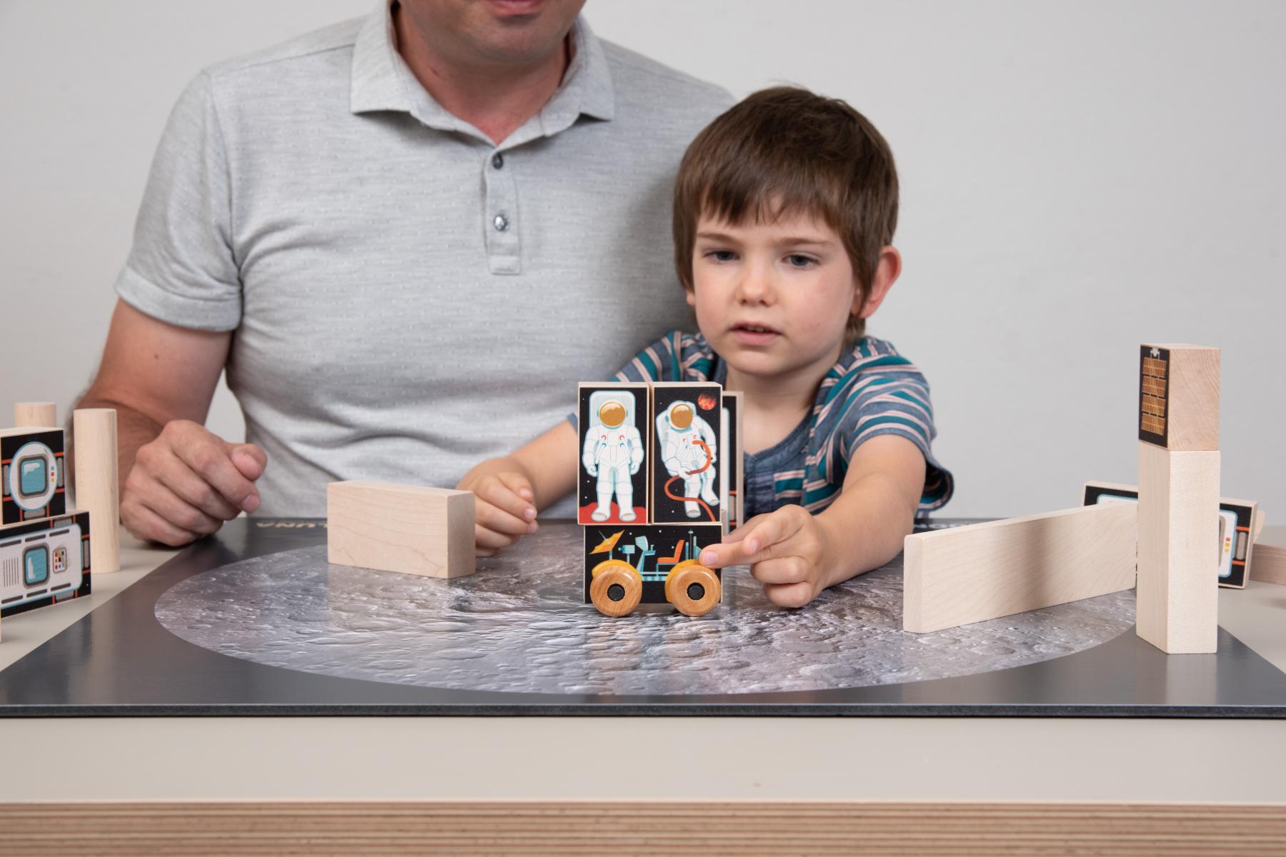 Facilitator and Learner use a block with a rover image to transport astronauts