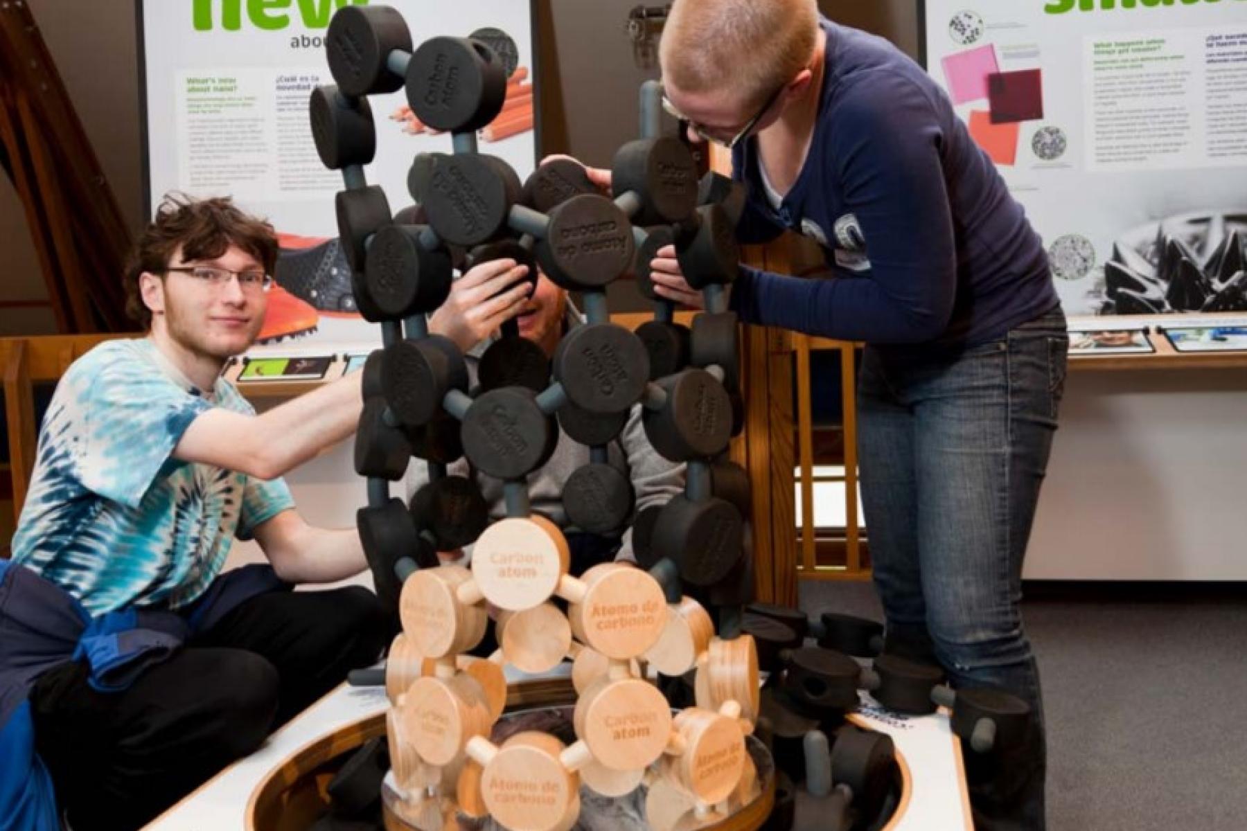 Learners using building a giant 3D image of a carbon nanotube from wooden blocks and black foam pieces