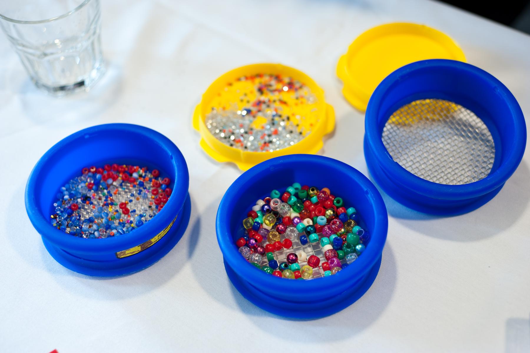 Learners pour beads into a sieve filter to sort by size